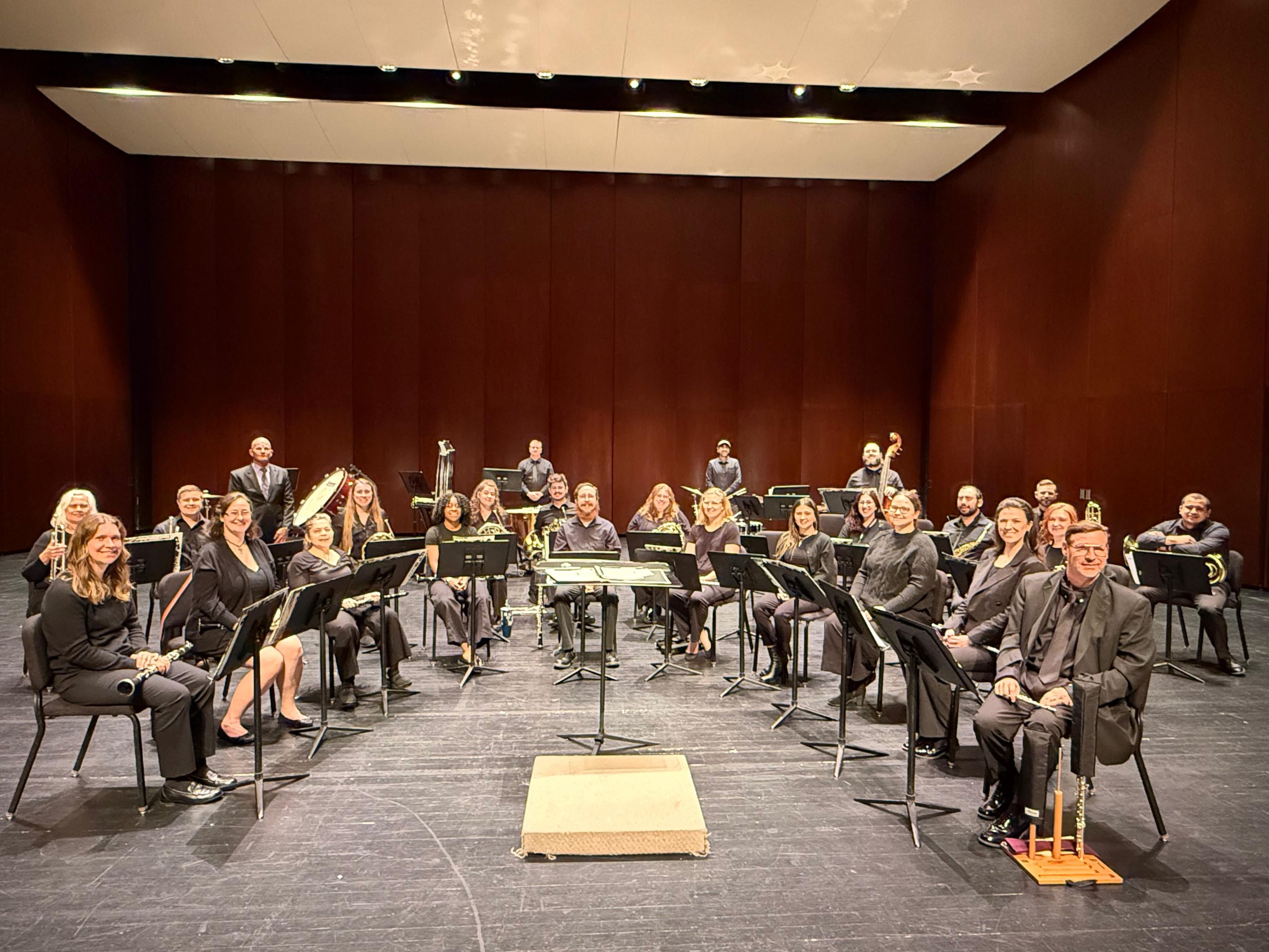 The full Dearborn Community Concert Band ensemble posed on stage at the Michael Guido Theater